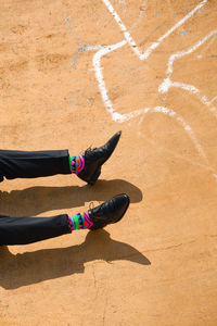 Low section of man wearing shoes while lying on land