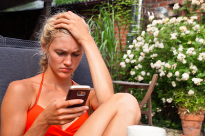 Tensed woman using phone while sitting on chair