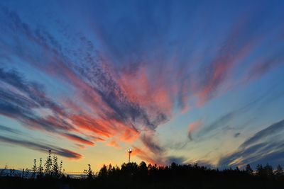 Low angle view of silhouette trees against dramatic sky