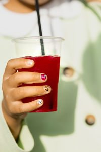 Hand of girl with painted nails holding strawberry granita