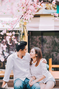 Smiling couple looking at each other while sitting on bench