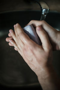 Close-up of man washing hands in sink