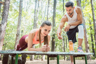 Man motivating woman in doing push ups at forest