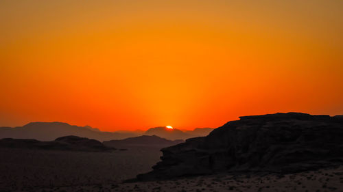 Scenic view of silhouette mountains against orange sky