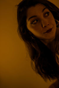 Close-up portrait of smiling young woman against yellow background