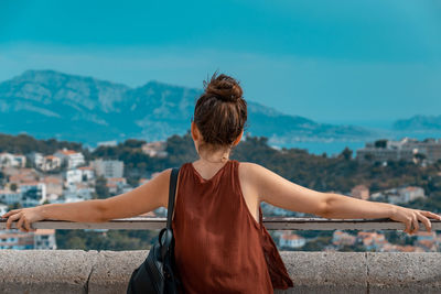 Rear view of woman with arms outstretched against cityscape