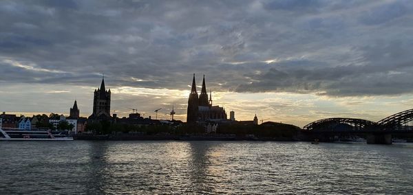 River in city against sky during sunset