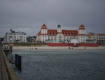 Houses by sea against sky in city