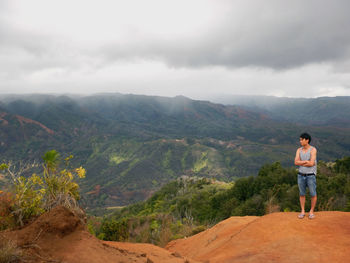 Rear view of man standing on mountain against sky