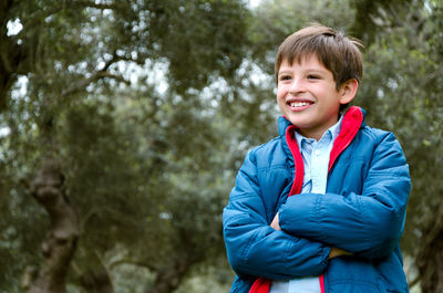 Portrait of smiling boy standing against trees