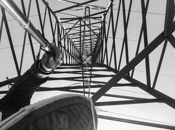 Cropped image of man taking self portrait of electricity pylon against clear sky