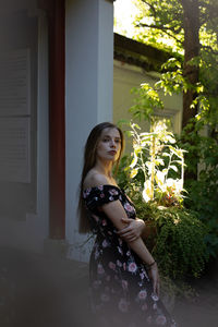 Portrait of young woman standing against wall