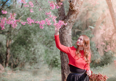 Woman standing by pink flower tree