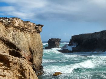 Rock formations by sea against sky