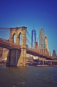 Brooklyn bridge over east river against clear blue sky in city