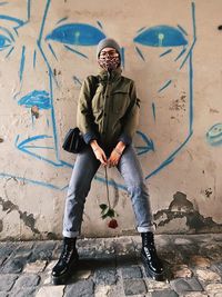 Full length of man standing against graffiti wall