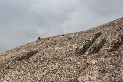 Man climbing on mountain against sky