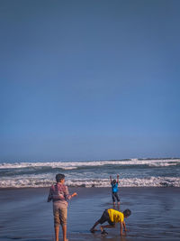 People on beach against blue sky