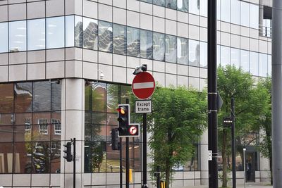 Road sign by street against sky in city