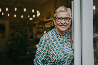 Portrait of senior female owner standing at entrance of store