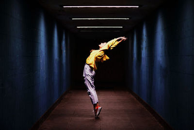 Full length of woman stretching in darkroom