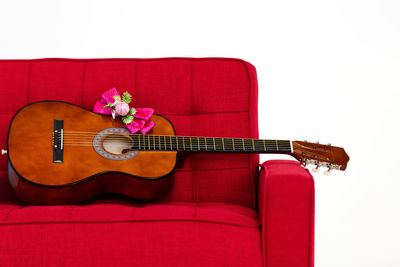 Red playing guitar on sofa against white background