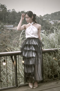 Young woman standing against plants