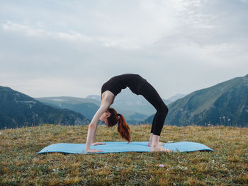 Full length of woman climbing on mountain against sky