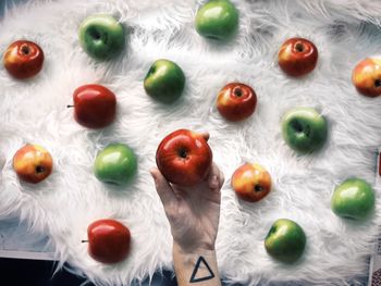 Cropped image of hand holding apple over fur