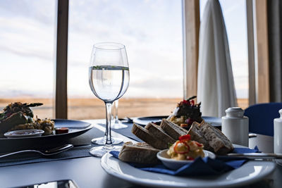 Tasty food and wineglasses on dining table against window at restaurant