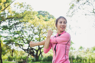 Portrait of smiling young woman standing against trees