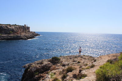 Rock formations by sea against clear sky