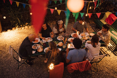 High angle view of multi-ethnic friends having dinner during garden party in backyard