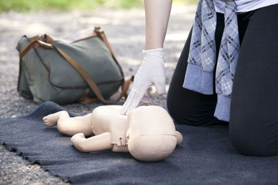 Midsection of paramedics performing cpr on baby mannequin