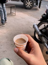 Midsection of person holding coffee cup on street