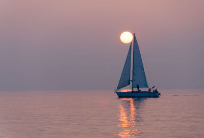 Sailboat sailing on sea against sky during sunset