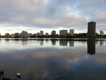 Reflection of buildings in lake against sky in city