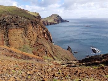 Scenic view of cliff by sea against sky