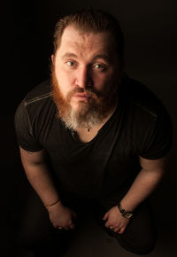 Portrait of man sitting against black background