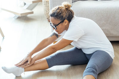 Side view of young woman exercising at home