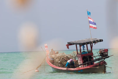 People on boat in sea against sky