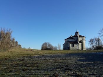 Church on field against clear blue sky