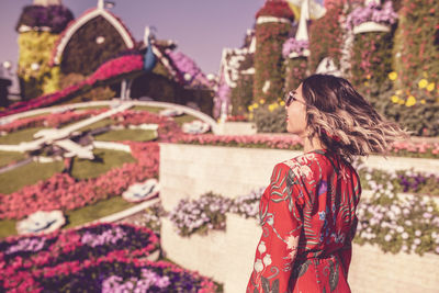 Side view of young woman tossing hair in ornamental garden 