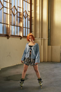 Young woman standing against window in building