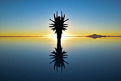 Silhouette palm tree against sea during sunset