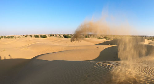 Sand dunes in desert against clear blue sky