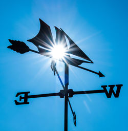 Low angle view of weather vane against blue sky