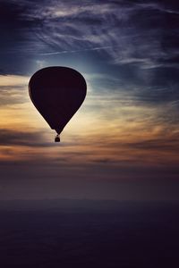 Hot air balloon flying over sea against sky during sunset