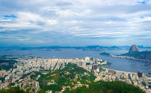 Aerial view of city by sea against sky