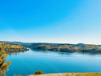 Scenic view of lake against clear blue sky